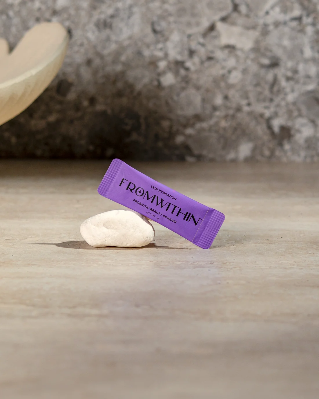 A FROMWITHIN sachet resting against a smooth stone